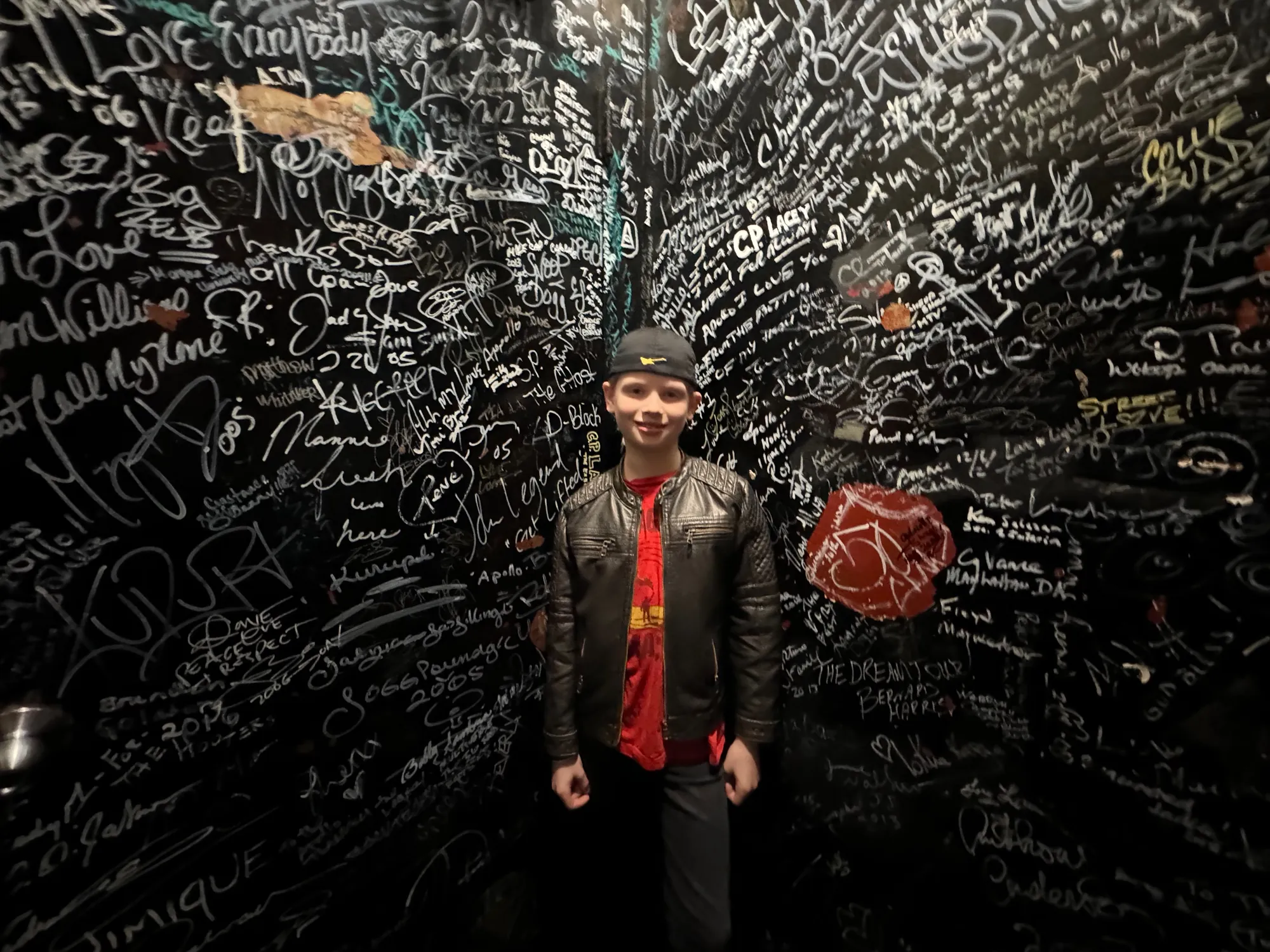 Aksel McDermott backstage in front of a wall covered in artists' signatures